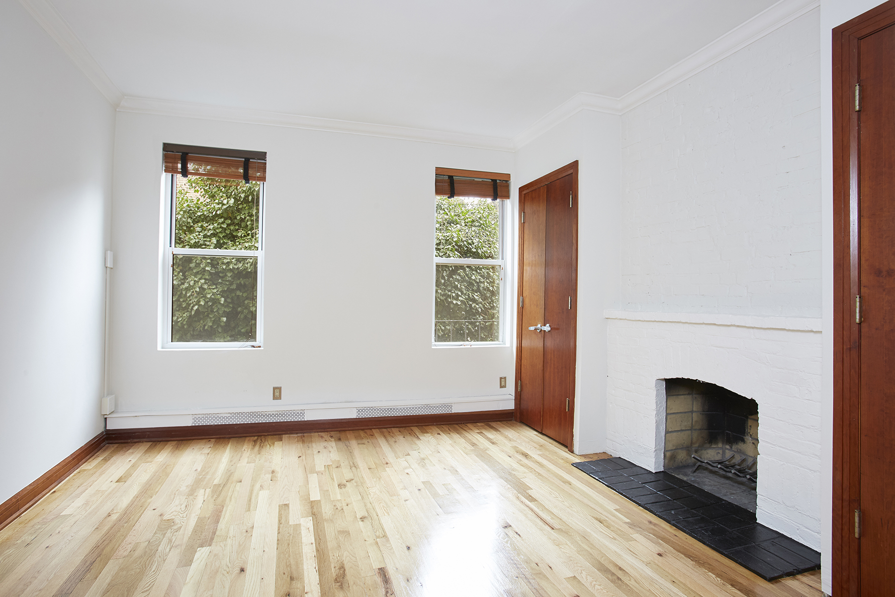 6 Bank Street, Unit 3 Manhattan, NY 10014 - Photo 3 of 6 an empty room with wooden floor fireplace and windows