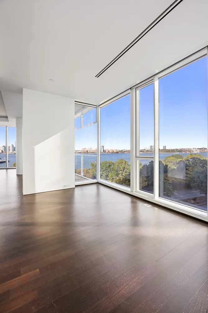 a view of empty room with wooden floor and floor to ceiling window