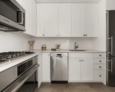 a kitchen with stainless steel appliances granite countertop white cabinets and a stove top oven