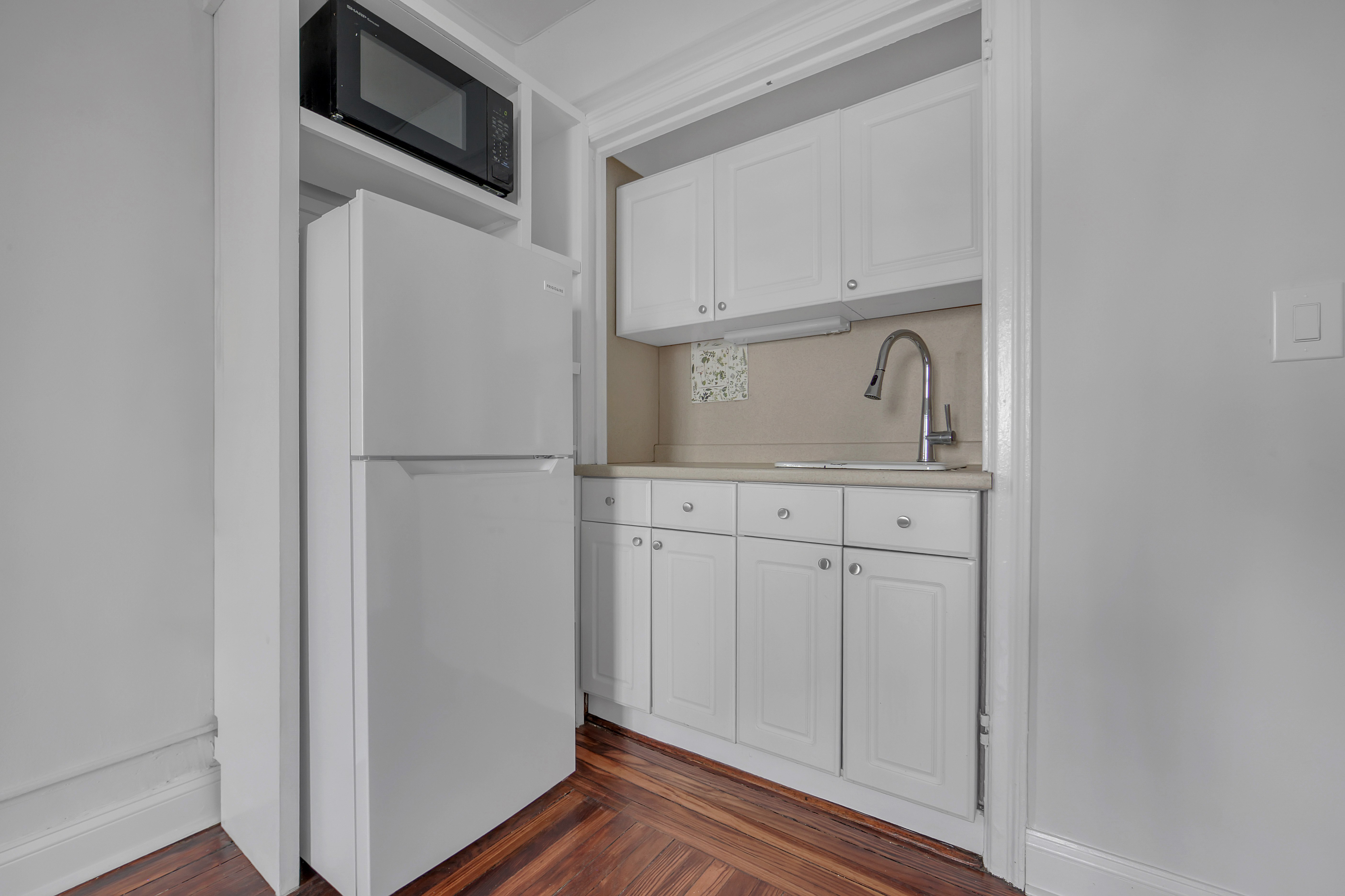 5 Tudor City Place, Unit 536 Manhattan, NY 10017 - Photo 8 of 14 a kitchen with white cabinets and white appliances