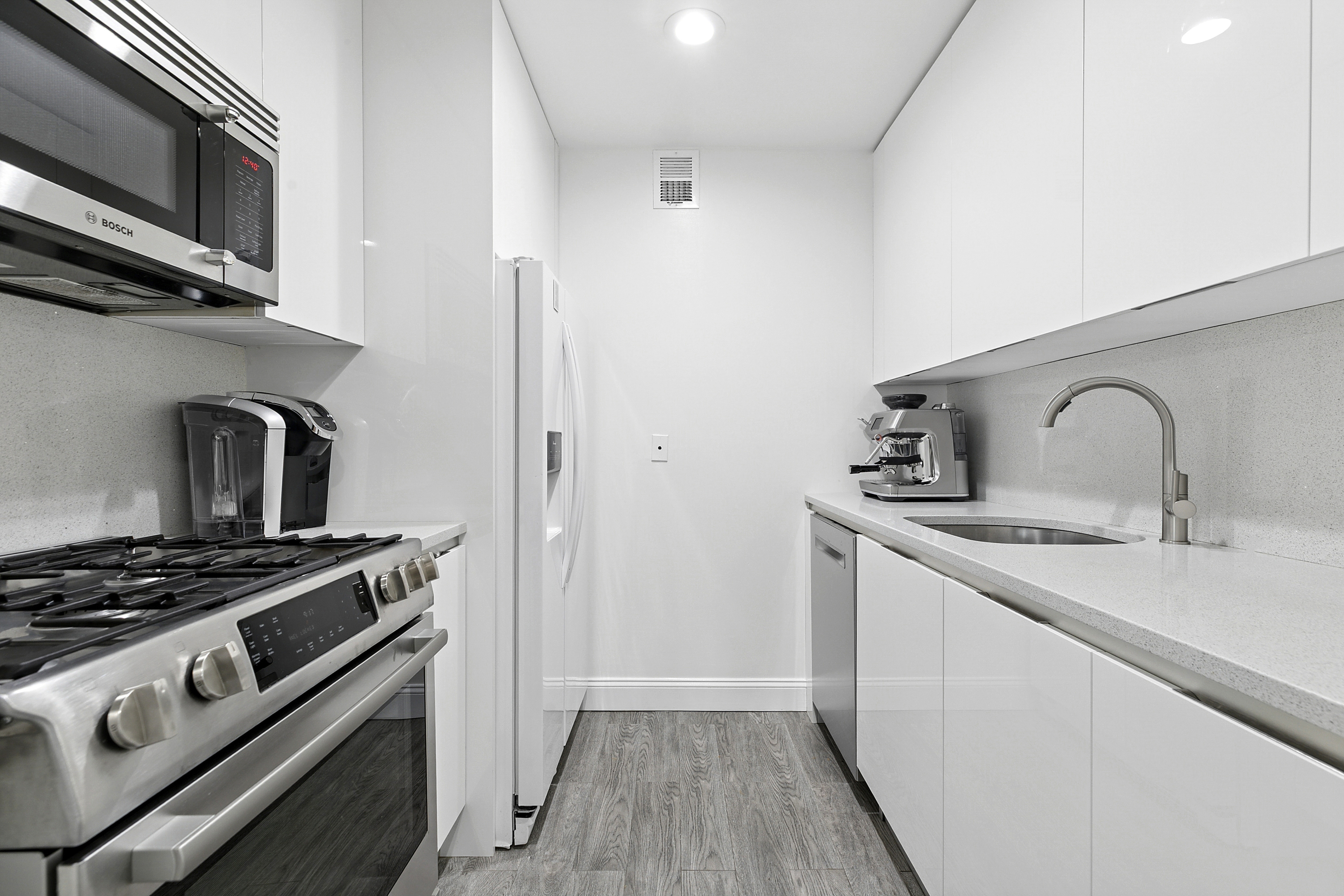 146 West 57th Street, Unit 47B Manhattan, NY 10019 - Photo 4 of 15 a kitchen with stainless steel appliances a sink stove and refrigerator