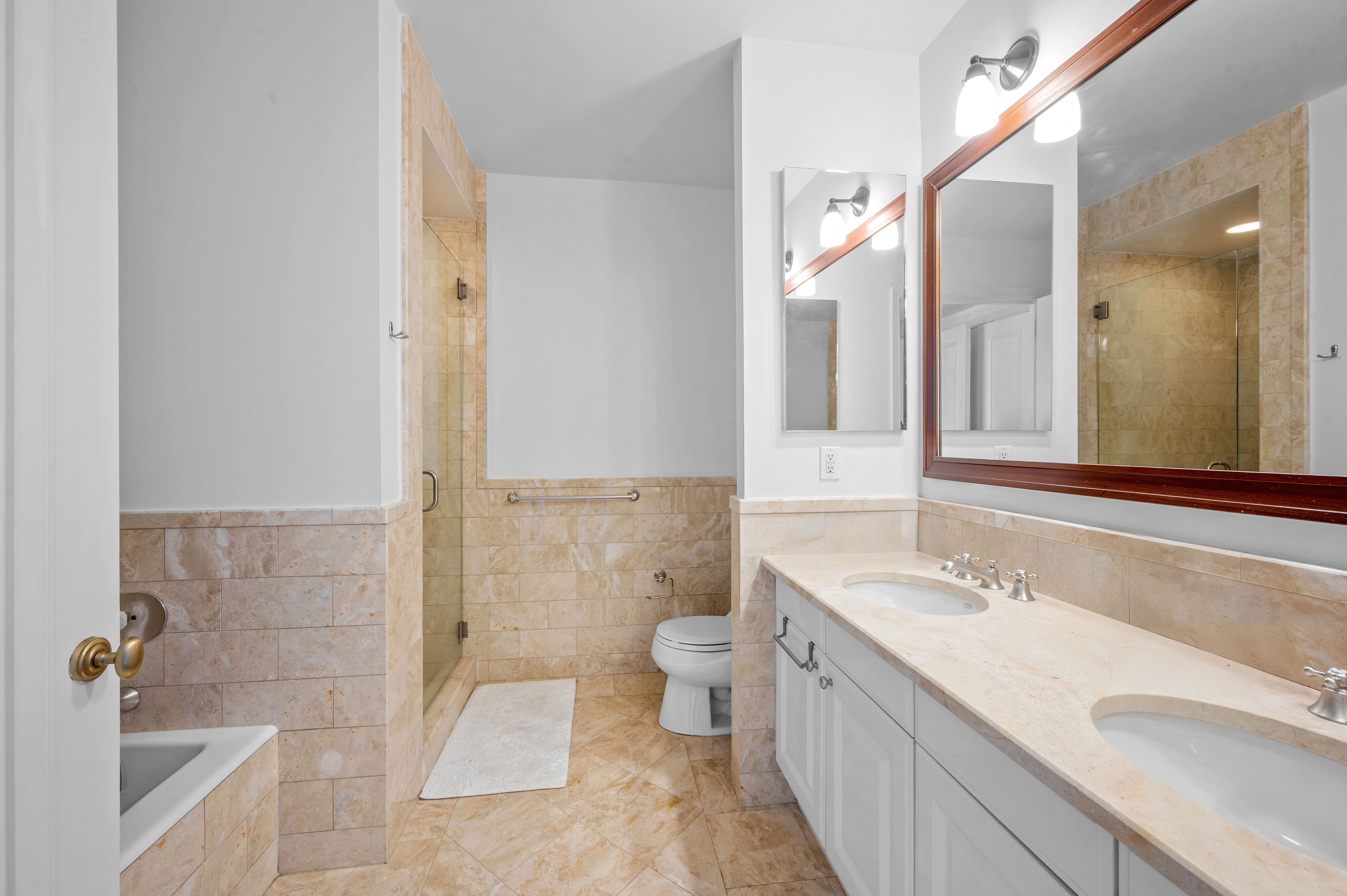 10 West Street, Unit 28C Manhattan, NY 10004 - Photo 7 of 12 a spacious bathroom with a granite countertop sink a toilet a mirror and shower