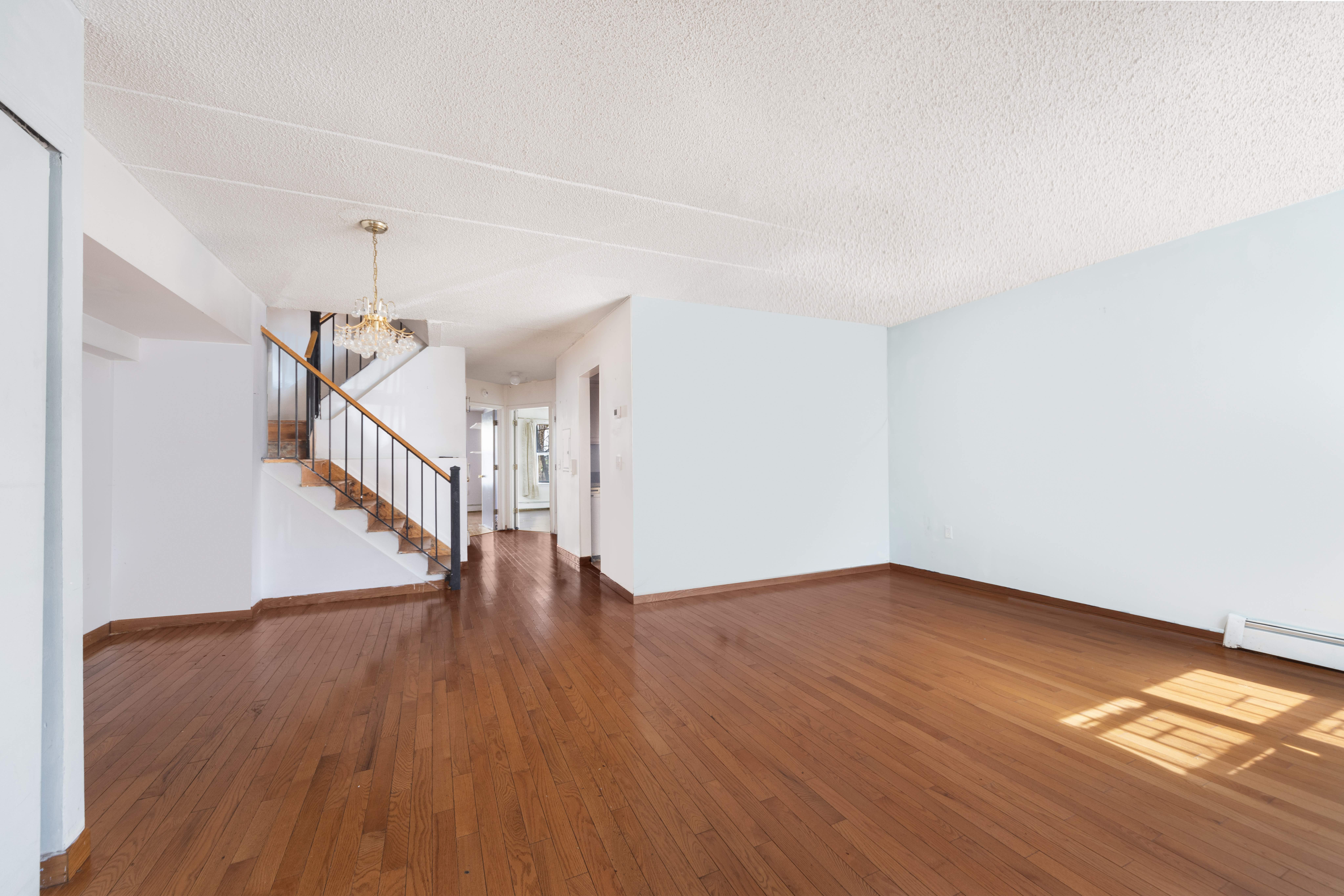 125 West 117th Street Manhattan, NY 10026 - Photo 4 of 23 a view of an empty room with wooden floor and stairs