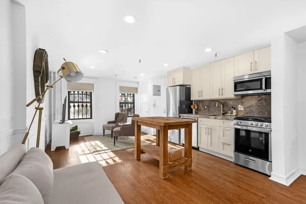 a living room with stainless steel appliances furniture and a kitchen view