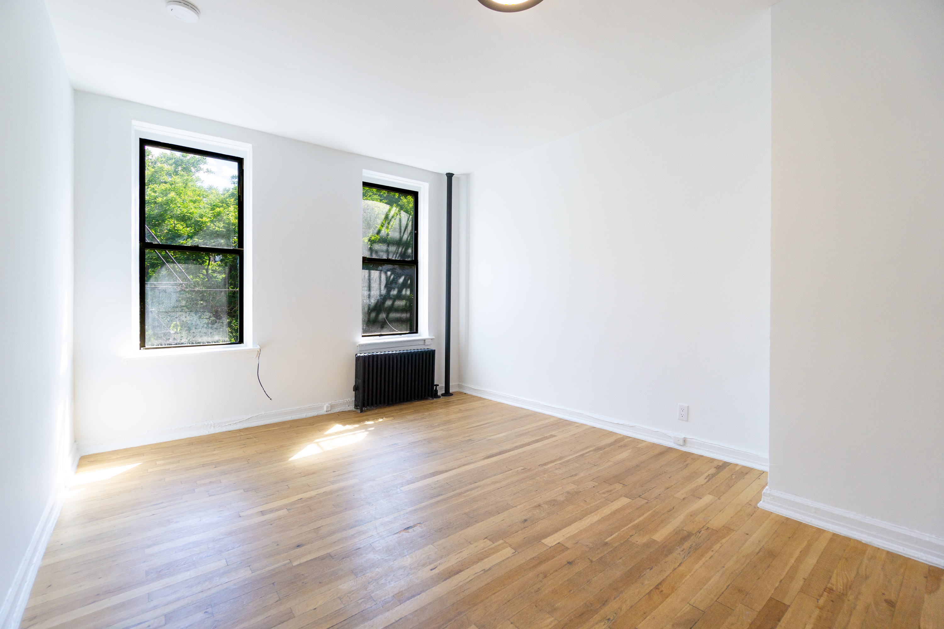 319 East 5th Street, Unit 9 Manhattan, NY 10003 - Photo 2 of 12 an empty room with wooden floor and windows