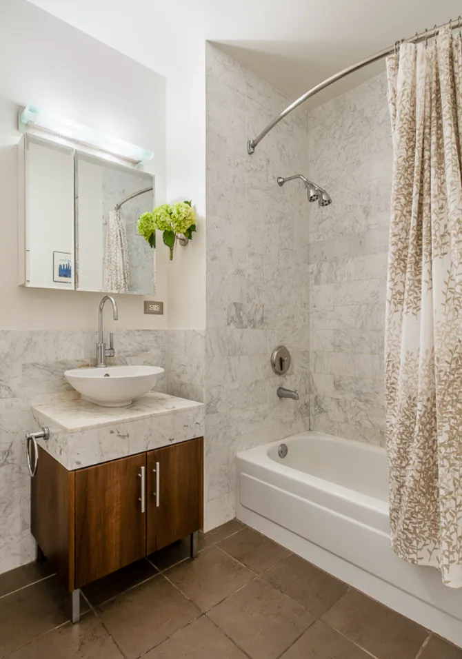 a bathroom with a granite countertop sink a mirror a bathtub and shower