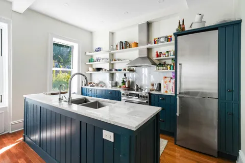 a kitchen with stainless steel appliances granite countertop a refrigerator a sink a stove and a dining table with wooden floor