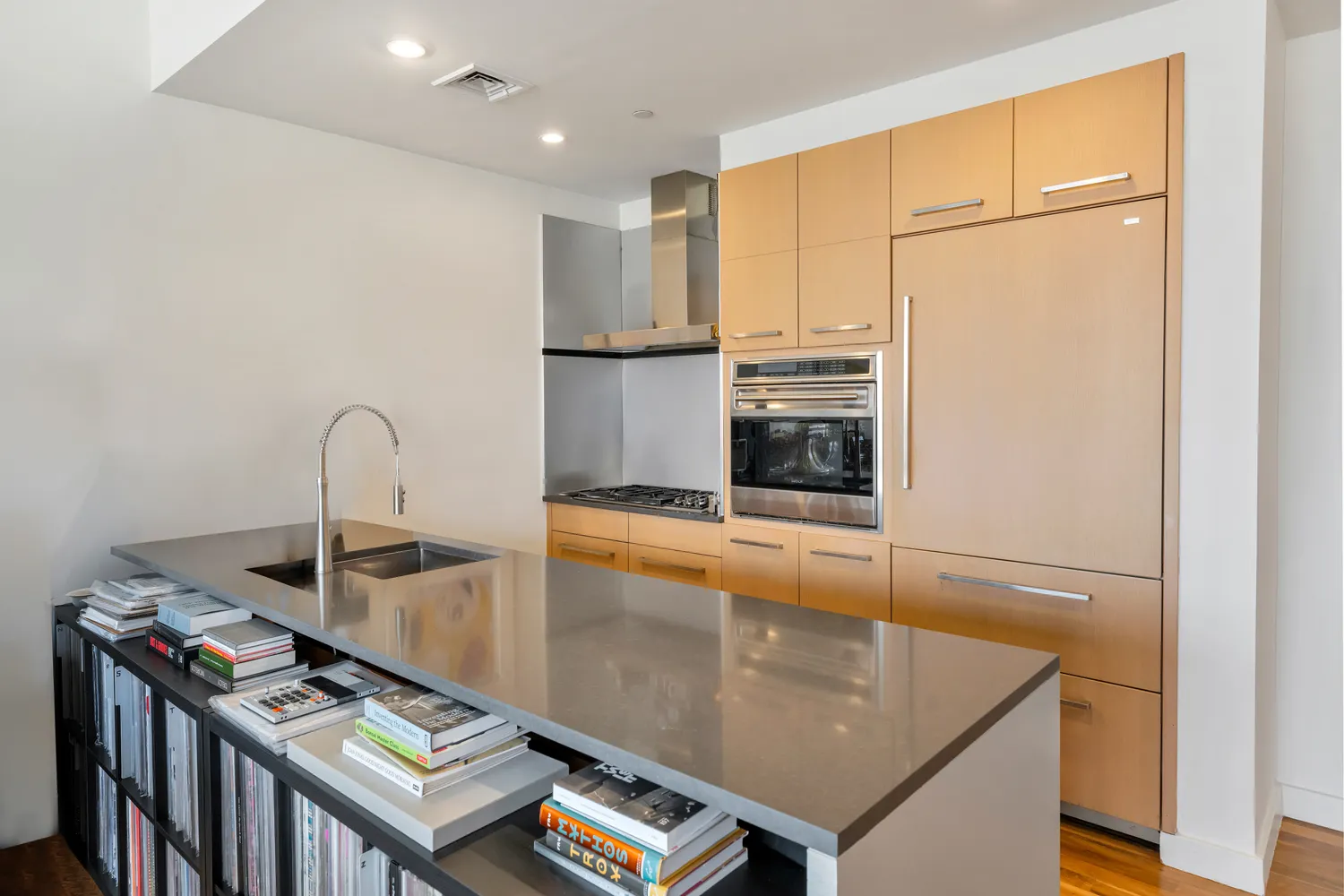 a kitchen with stainless steel appliances granite countertop a refrigerator a stove and a sink with wooden floor