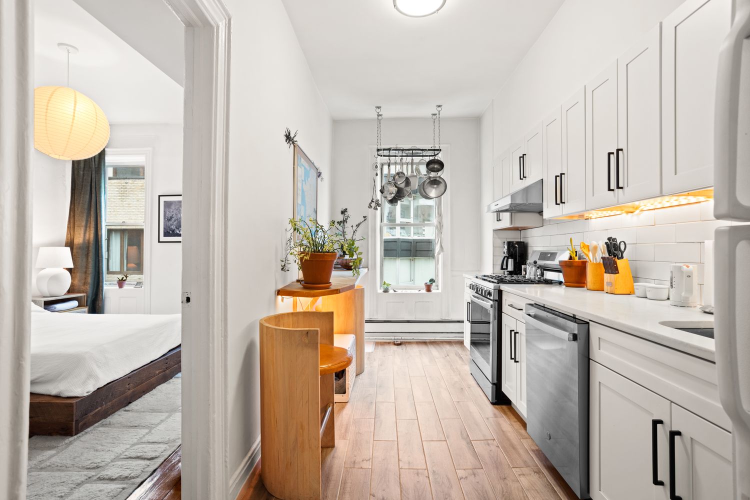 a kitchen with stainless steel appliances a refrigerator a sink dishwasher and white cabinets with wooden floor