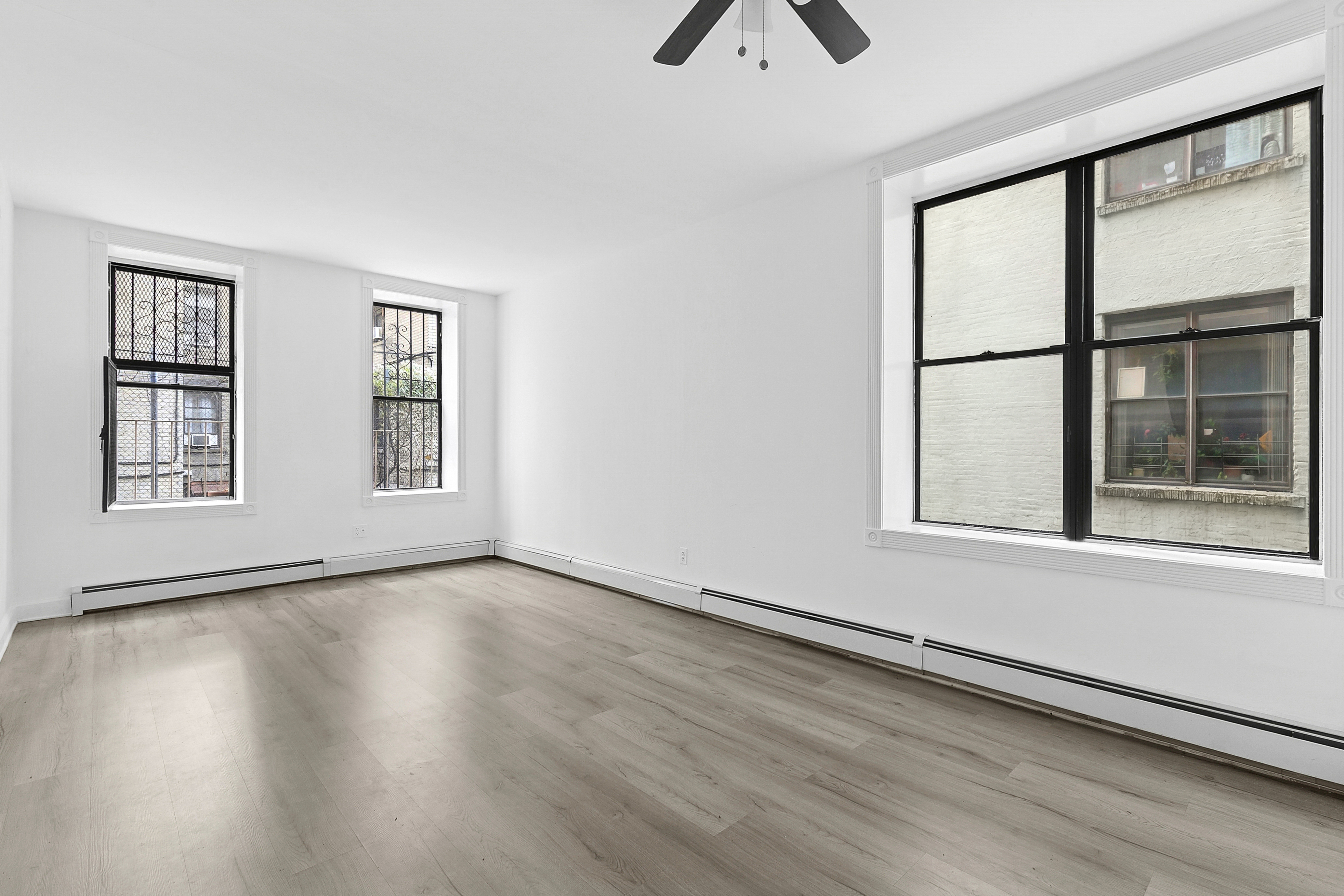 178 East 2nd Street, Unit 1B Manhattan, NY 10009 - Photo 4 of 11 an empty room with wooden floor and windows