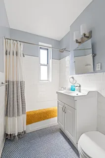 a bathroom with a sink a toilet a window a bathtub and vanity