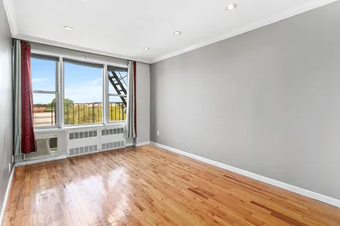 a view of an empty room with a window and wooden floor
