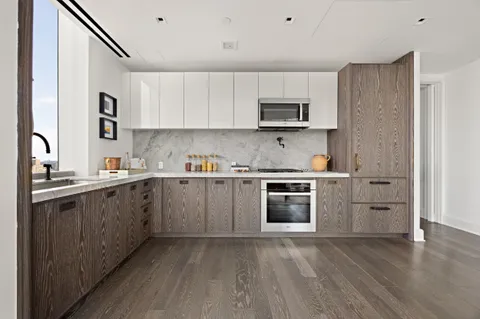 a kitchen with stainless steel appliances granite countertop a refrigerator stove a sink and white cabinets with wooden floor