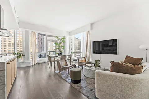 a living room with furniture wooden floor and a floor to ceiling window