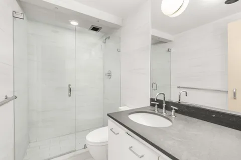 a bathroom with a granite countertop sink toilet mirror and shower