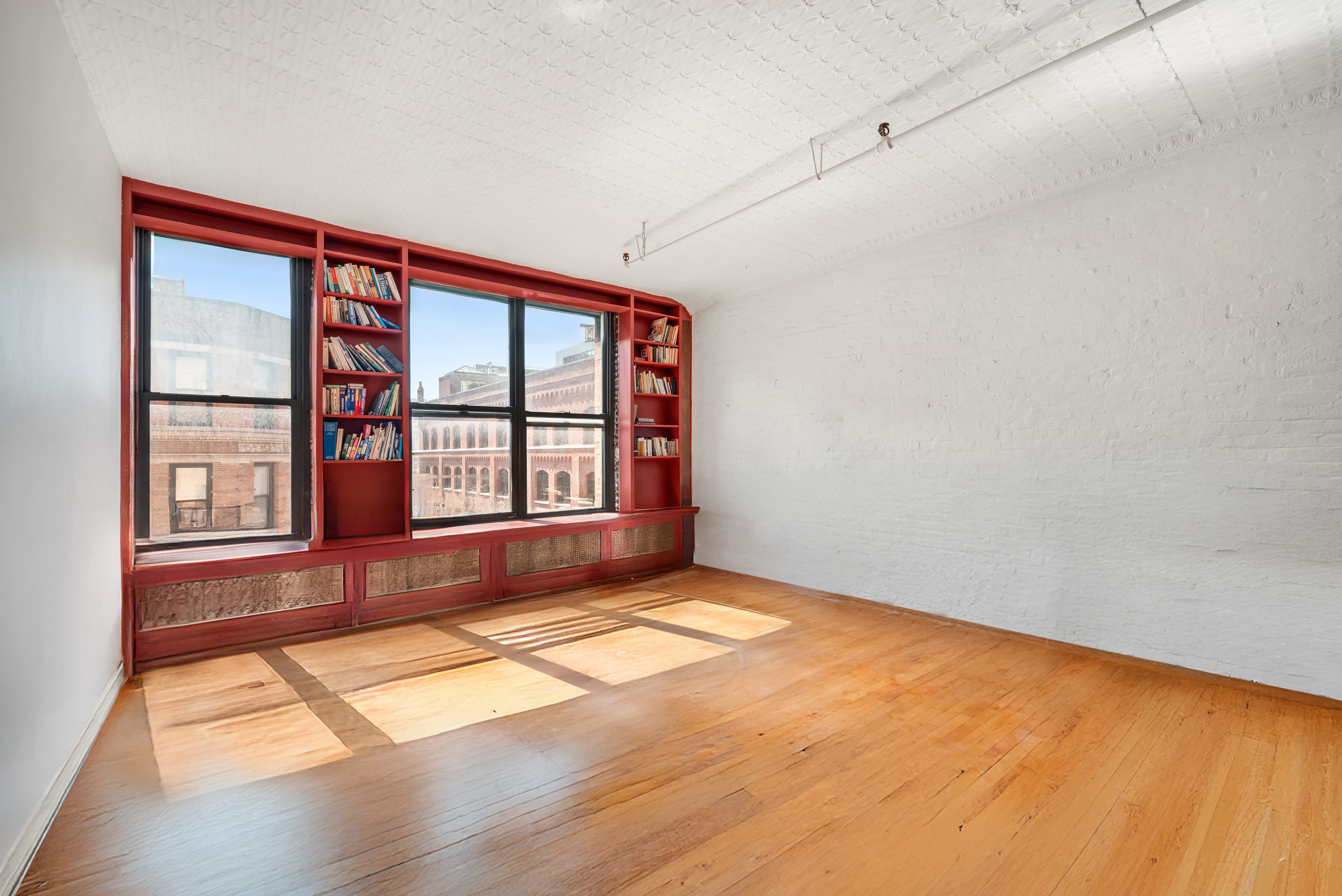 27 Bleecker Street, Unit 6B Manhattan, NY 10012 - Photo 3 of 7 an empty room with a fireplace and windows