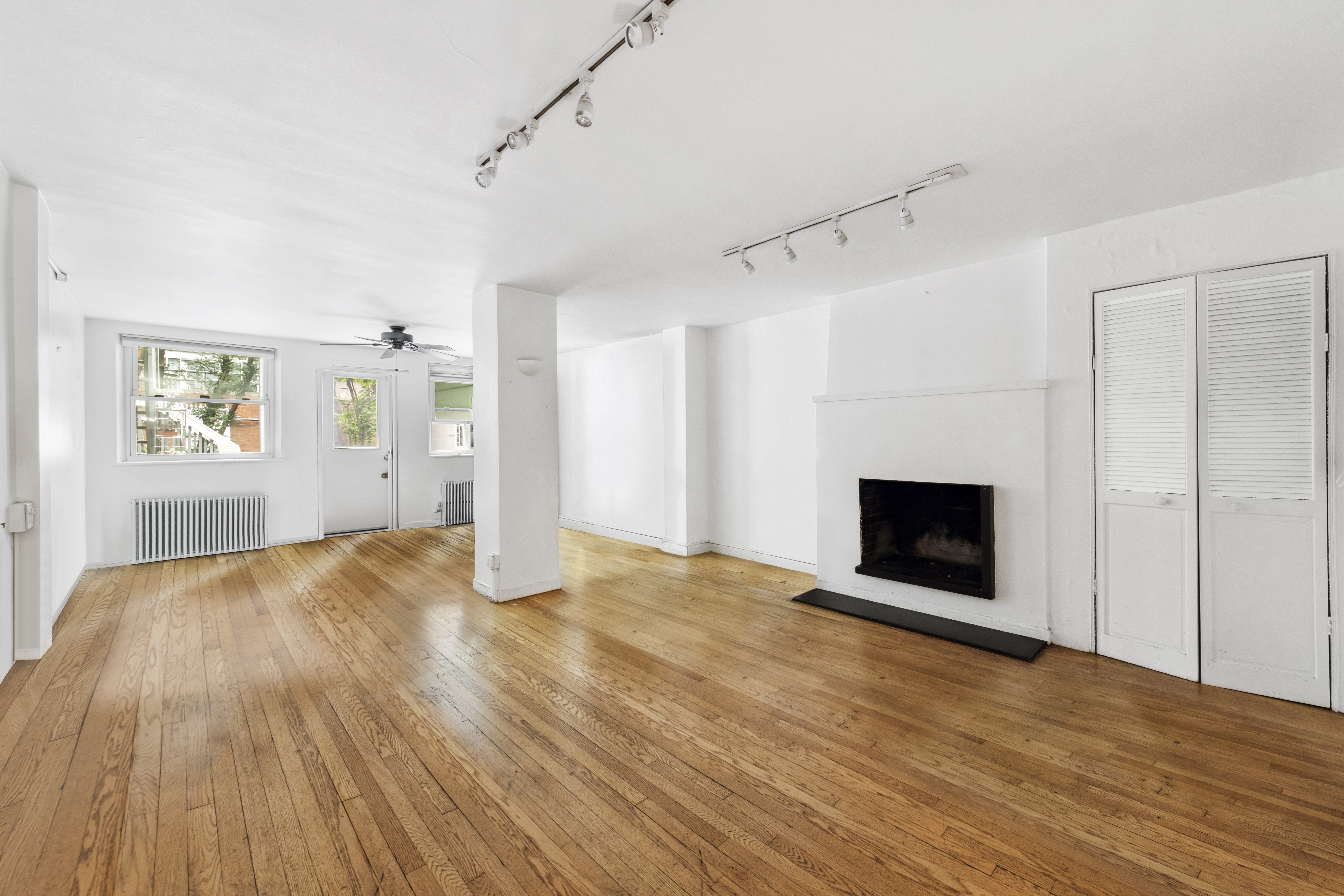 209 East 48th Street Manhattan, NY 10017 - Photo 2 of 13 a view of empty room with wooden floor and fireplace