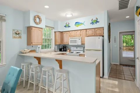 a kitchen with stainless steel appliances granite countertop a refrigerator a sink a stove and a dining table
