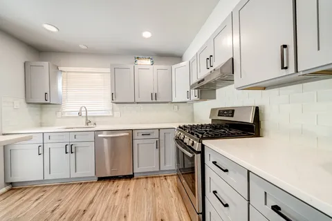 a kitchen with cabinets appliances wooden floor and a window