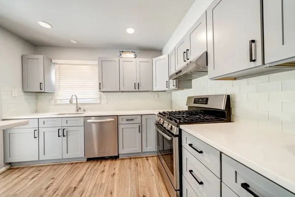 a kitchen with cabinets appliances wooden floor and a window
