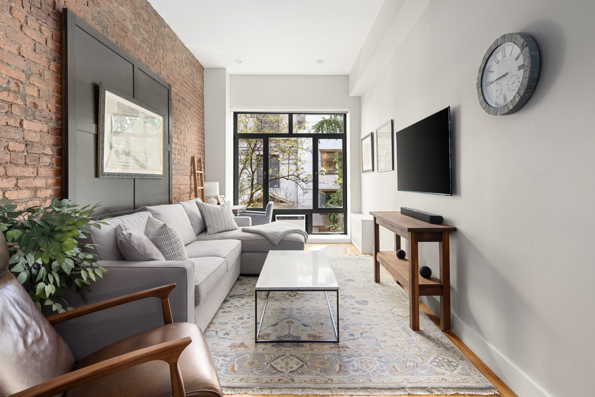 a living room with furniture a flat screen tv and a floor to ceiling window
