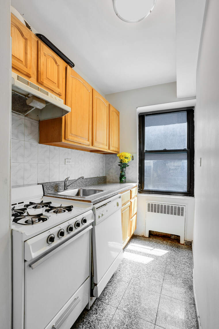 210 East 47th Street, Unit 7J Manhattan, NY 10017 - Photo 11 of 12 a kitchen with stainless steel appliances granite countertop a stove a sink and a microwave