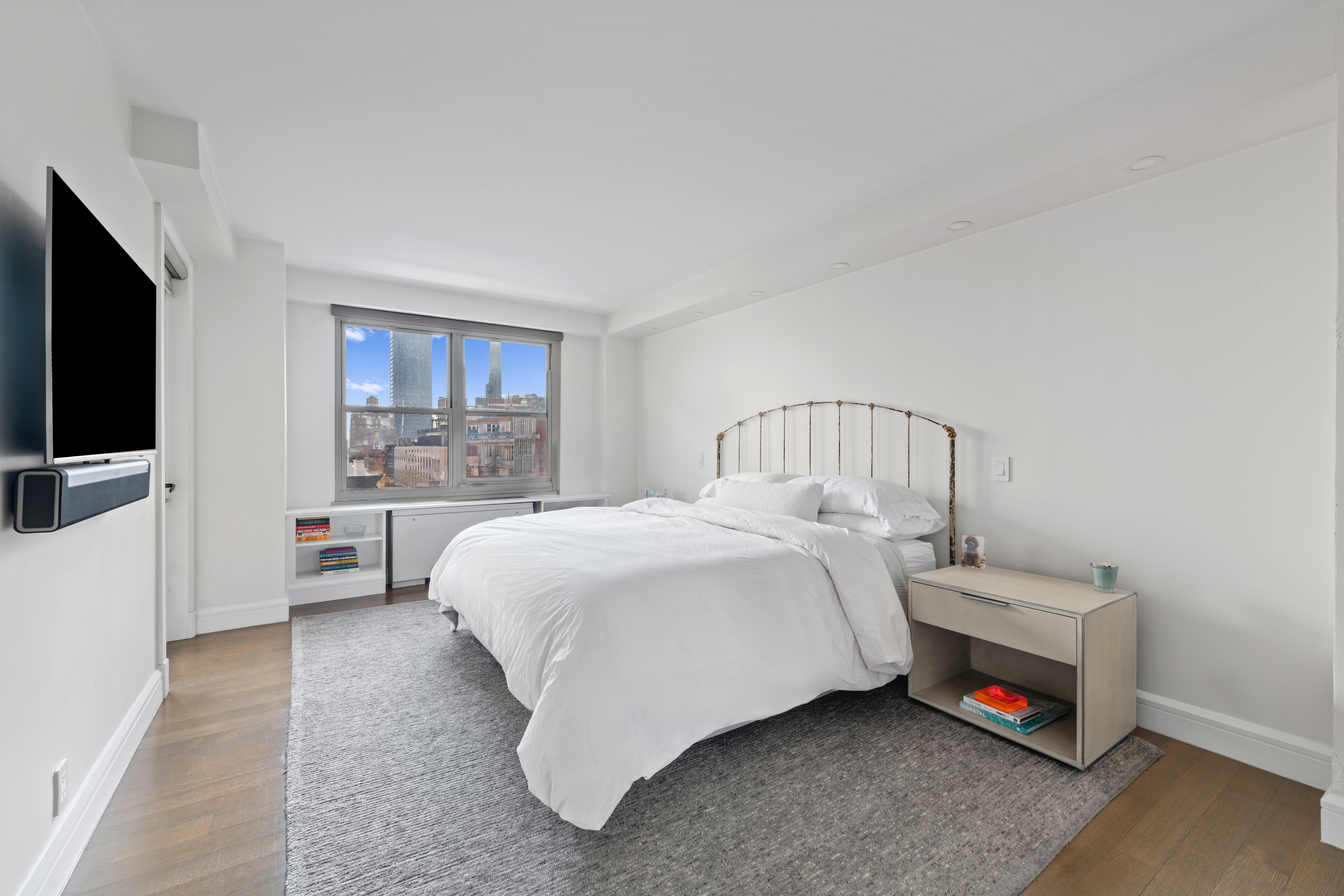 363 East 76th Street, Unit 7C Manhattan, NY 10021 - Photo 7 of 19 a bedroom with a bed a mirror and a flat tv screen on a table