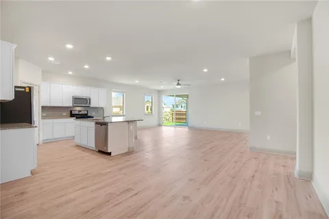 a view of kitchen with kitchen island granite countertop stainless steel appliances refrigerator sink and cabinets