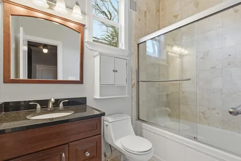 a bathroom with a granite countertop sink a toilet and shower