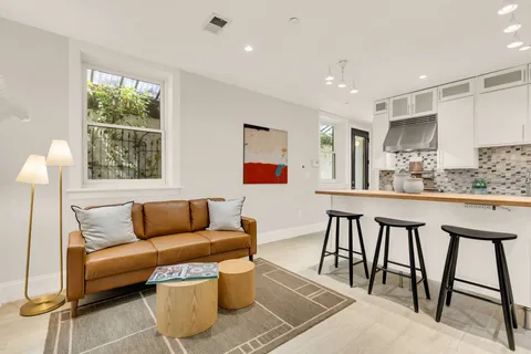 a dining hall with stainless steel appliances kitchen island granite countertop a dining table chairs and a sink