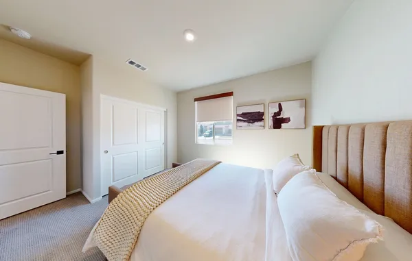 a bedroom with a bed and a lamp on dresser