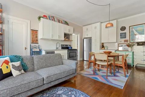 a living room with furniture kitchen view and a window