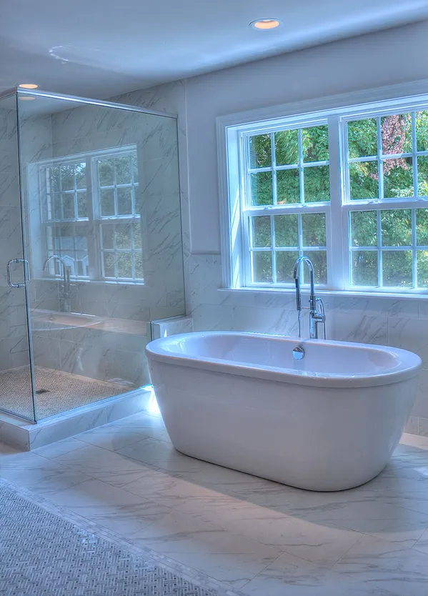 a white bath tub sitting in a bathroom next to a window
