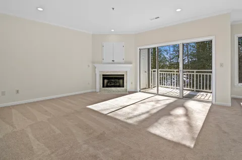 a view of empty room with floor to ceiling window and fireplace