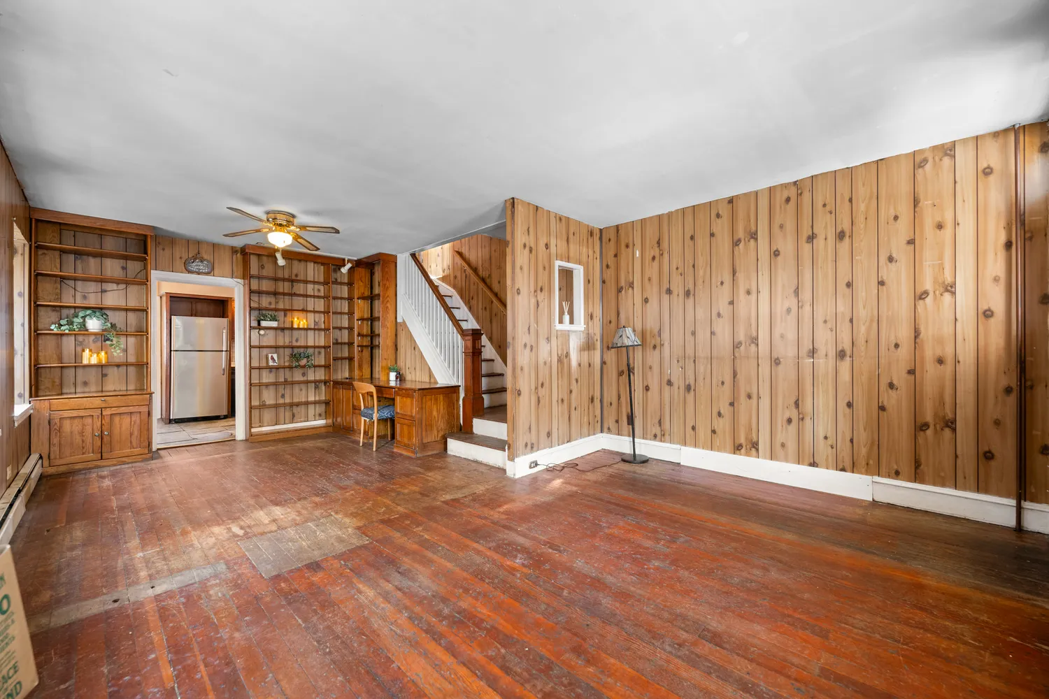 a view of an empty room with wooden floor and stairs