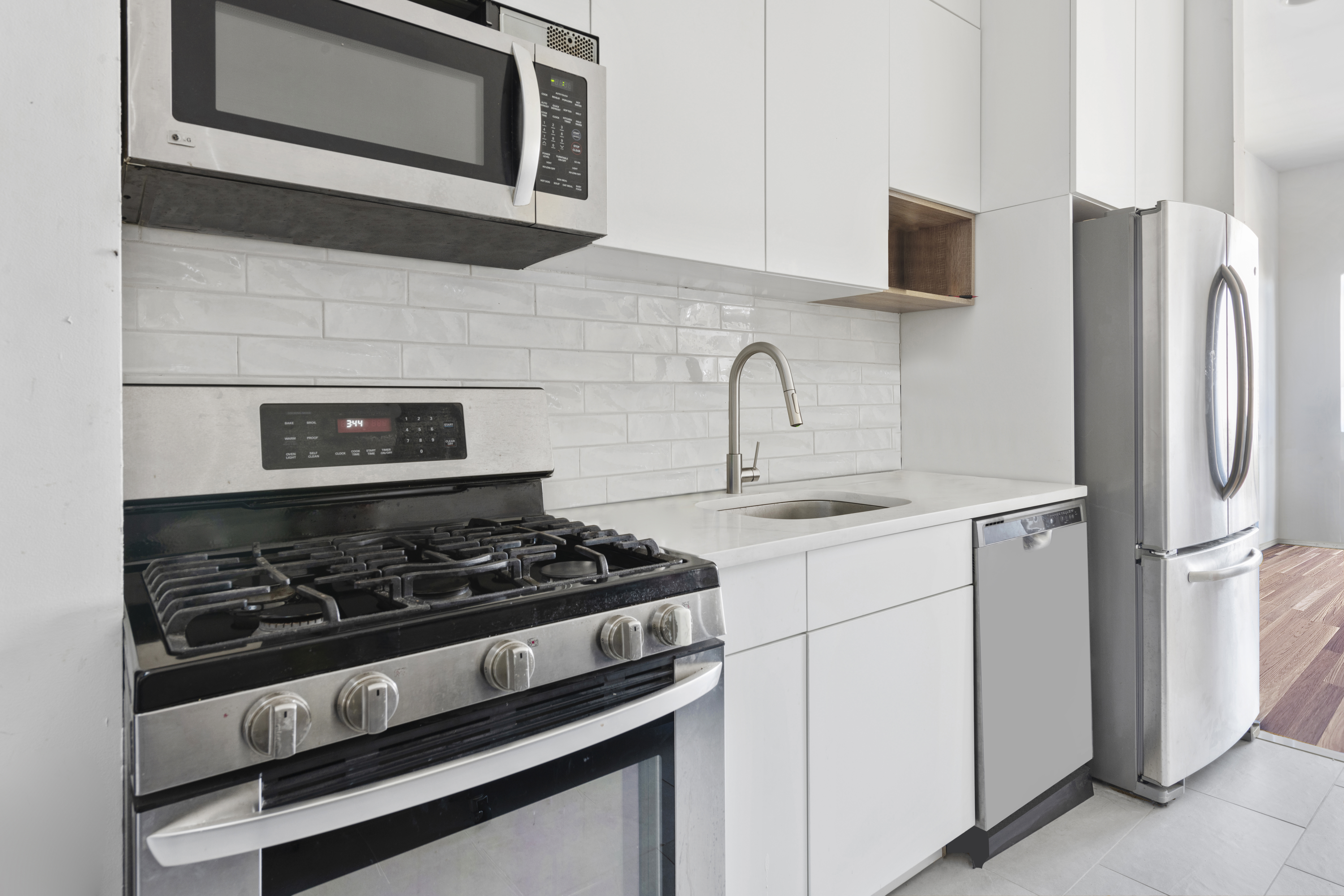 221 Troutman Street, Unit 4L Brooklyn, NY 11237 - Photo 5 of 11 a kitchen with stainless steel appliances granite countertop white cabinets and a stove top oven