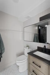 a bathroom with a granite countertop sink a toilet and a mirror