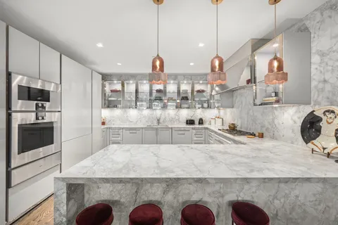 a large kitchen with kitchen island granite countertop a sink a counter space stainless steel appliances and cabinets