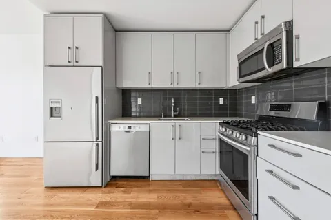 a kitchen with cabinets stainless steel appliances and wooden floor