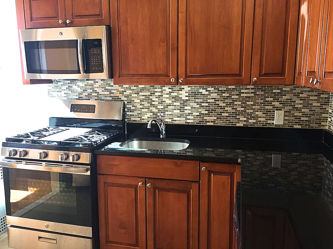 68-64 Yellowstone Boulevard, Unit A36 Queens, NY 11375 - Photo 2 of 4 a kitchen with stainless steel appliances granite countertop a stove a sink and a microwave