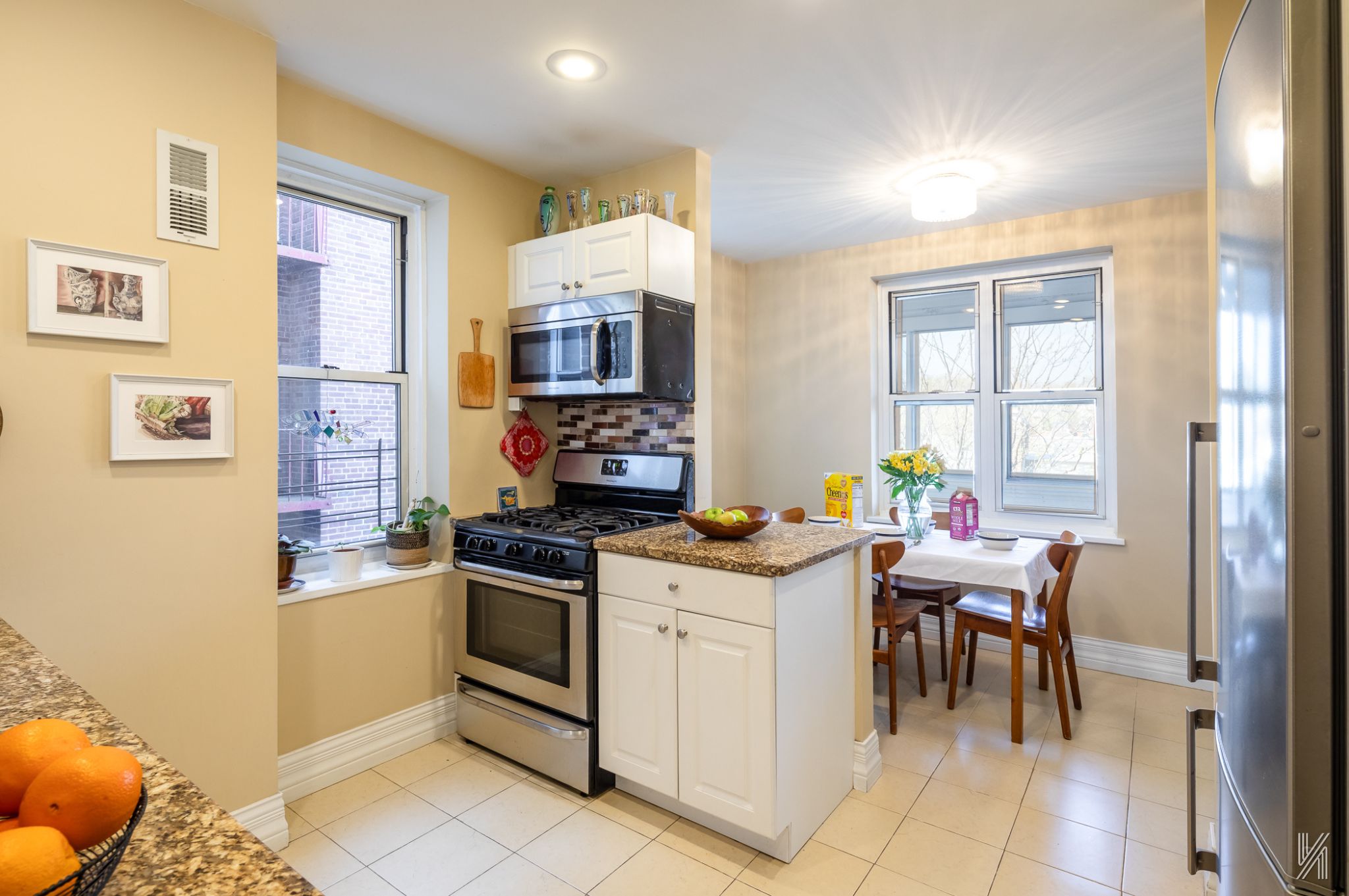 34-41 85th Street, Unit 4P Queens, NY 11372 - Photo 8 of 20 a kitchen with stainless steel appliances granite countertop a stove top oven a sink a dining table and chairs with wooden floor