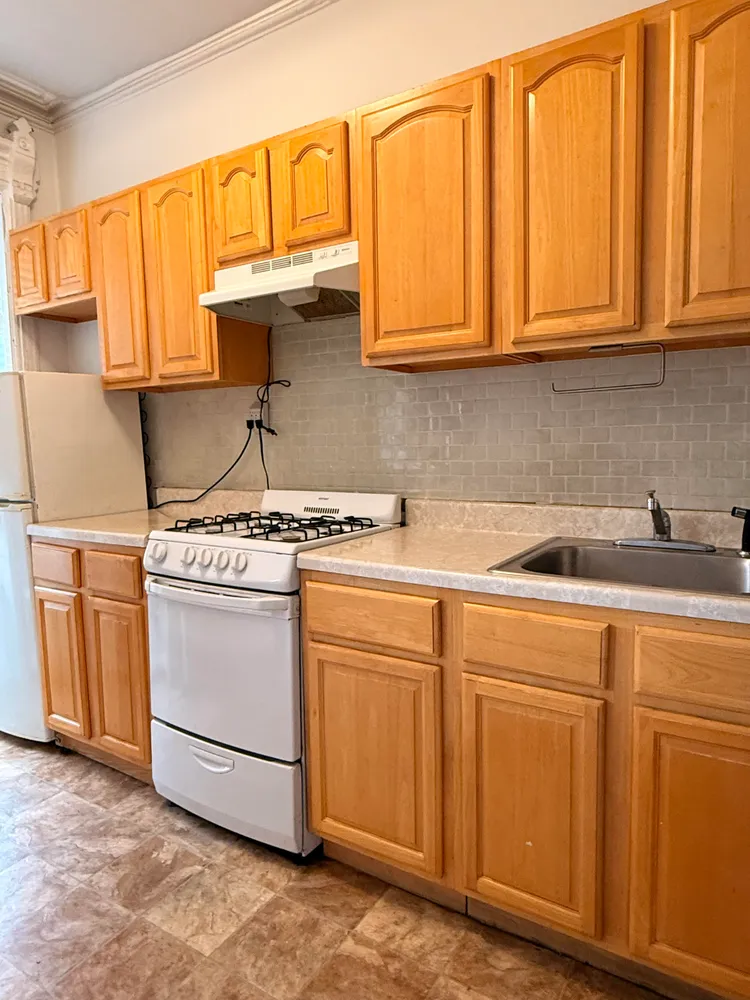 a kitchen with stainless steel appliances granite countertop a sink a stove and white cabinets with wooden floor