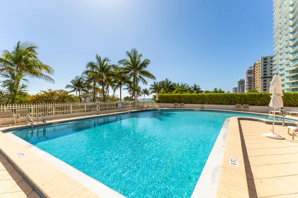 a view of a palm trees and dinning area with swimming pool