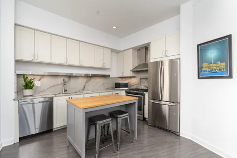 a kitchen with stainless steel appliances granite countertop a refrigerator a sink a stove and white cabinets