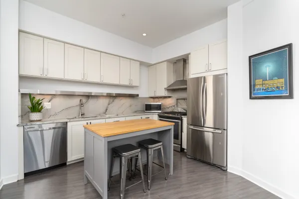 a kitchen with stainless steel appliances granite countertop a refrigerator a sink a stove and white cabinets