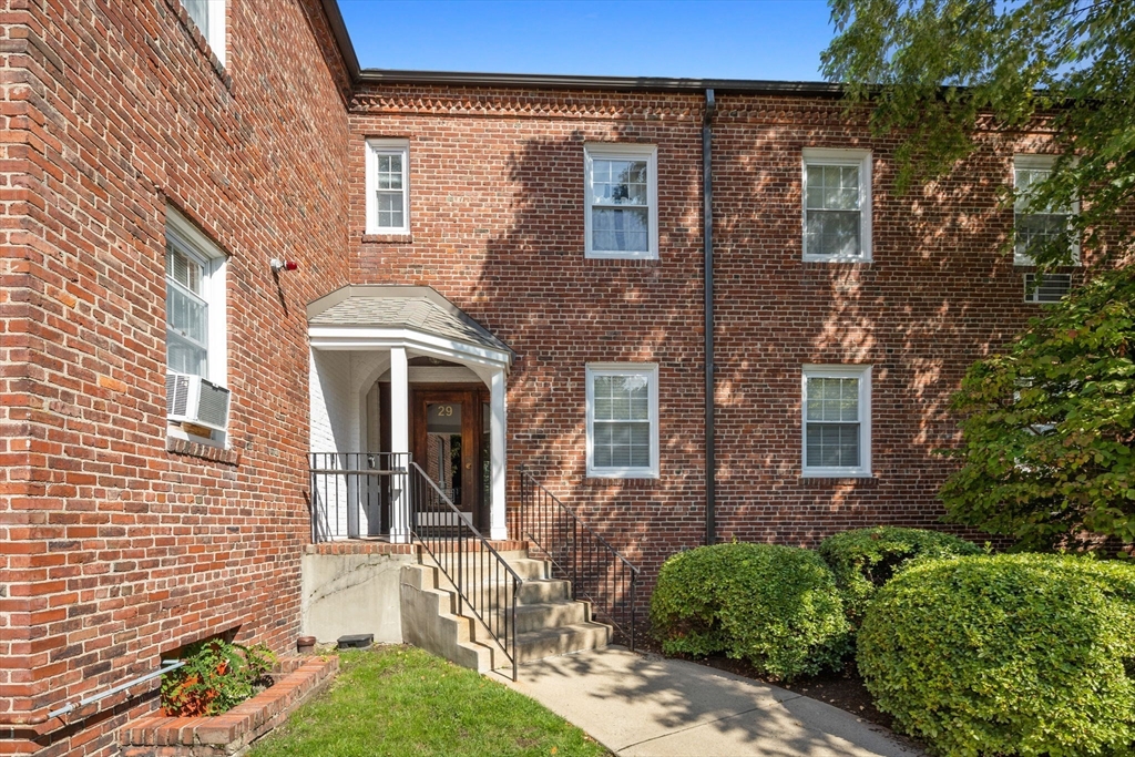27-29 Commonwealth Avenue, Unit 9 Newton, MA 02467 - Photo 17 of 20 front view of a brick house with a small yard
