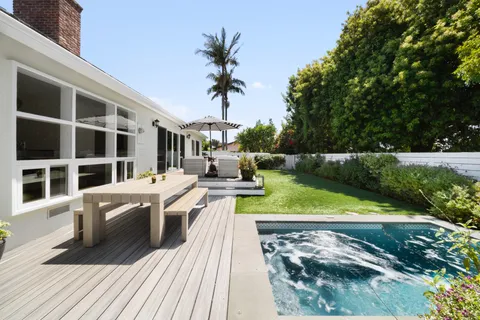 a view of a house with pool lawn chairs and wooden fence
