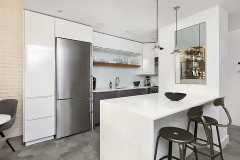 a kitchen with stainless steel appliances a refrigerator a sink a table and chairs
