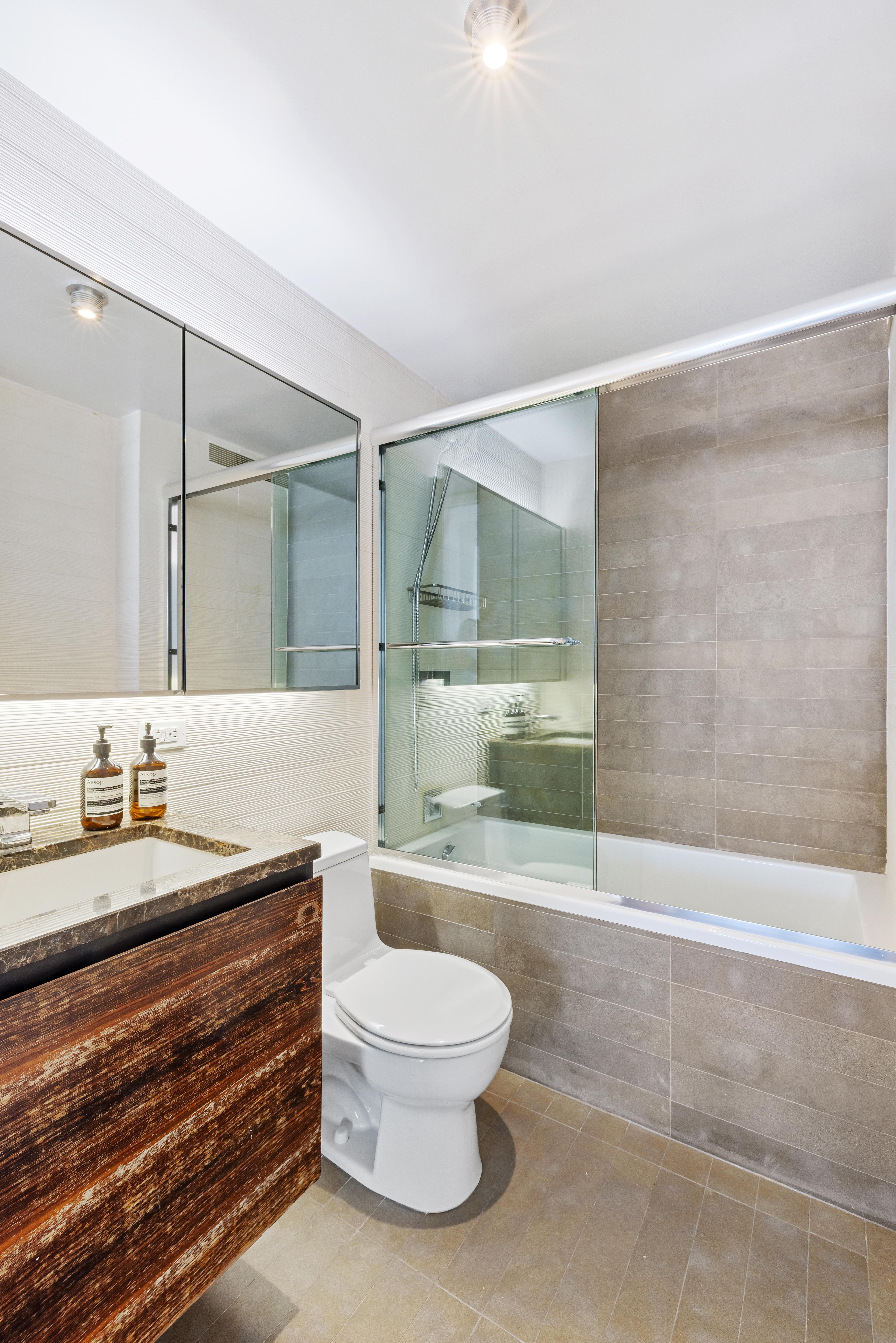 515 East 72nd Street, Unit 40E Manhattan, NY 10021 - Photo 15 of 34 a bathroom with a granite countertop sink a toilet a mirror and shower