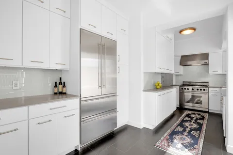 a kitchen with stainless steel appliances a refrigerator a stove a sink and white cabinets